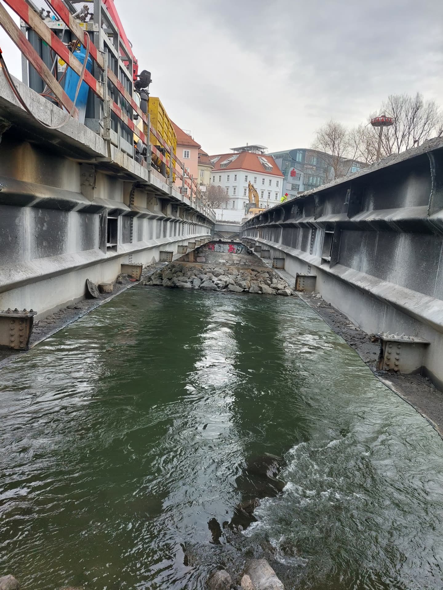 Freier Kanal zwischen zwei Stahlträgersträngen über dem Wasser, Material an der Seite abgelegt.