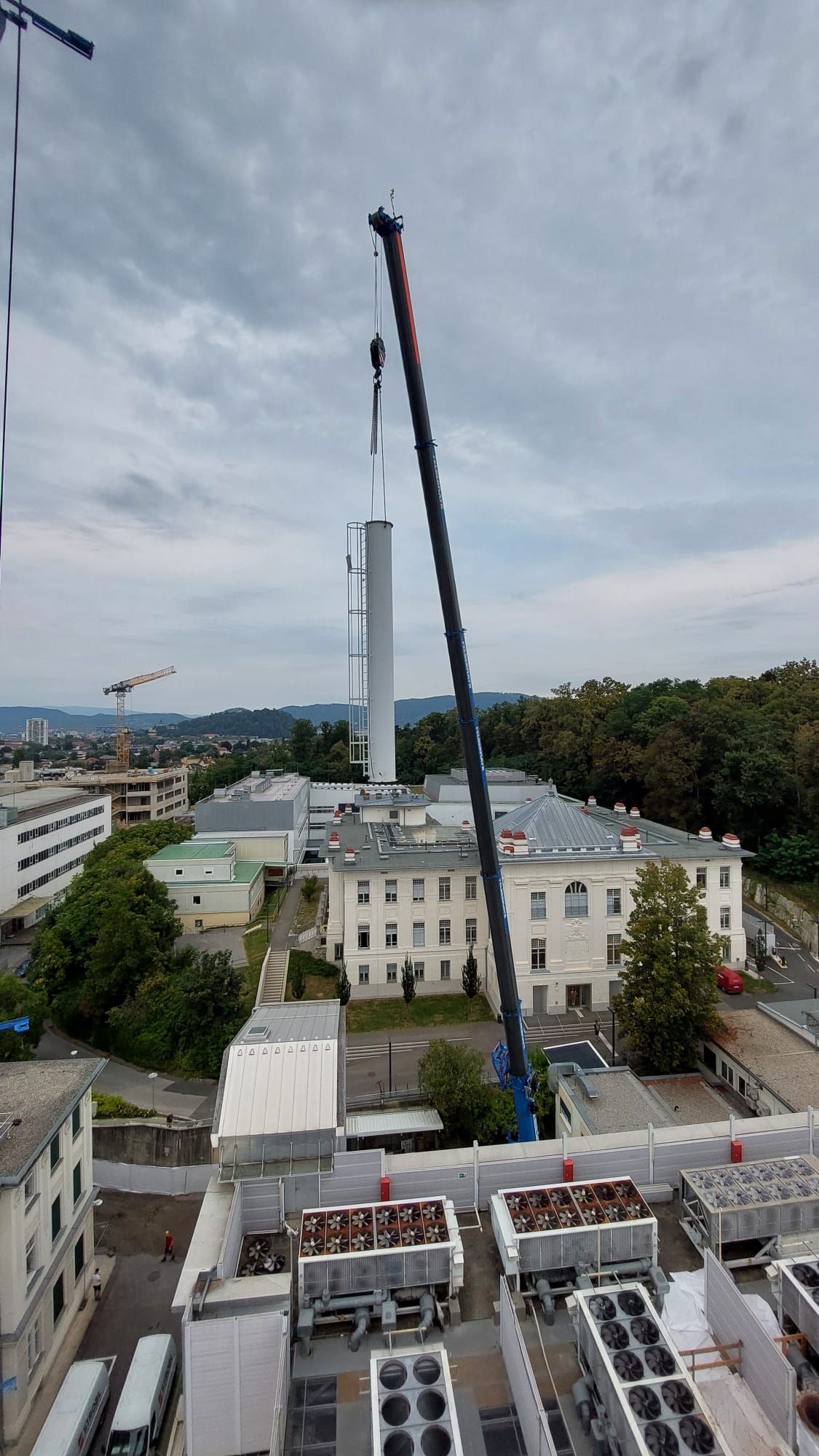 Mobilkran hebt einen hohen weißen Schlot, Ausleger schräg.