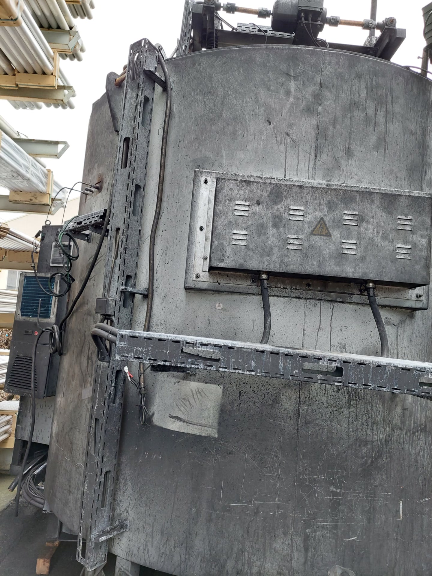 Grauer Industrieofen im Freien, Kabel gelöst, Schaltschrank seitlich.